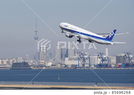 東京スカイツリーと高層ビル群を背景に離陸する航空機 羽田空港 東京都大田区の写真素材