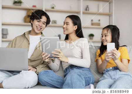 Happy korean millennial woman showing to husband and teen daughter video, advertisement and offer on tablet 85698949