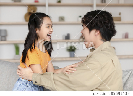 Happy asian millennial man and teen daughter look at each other with open mouths, have fun 85699532