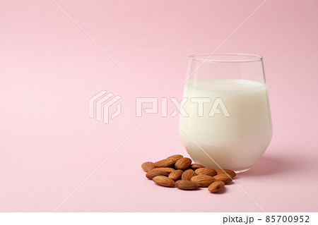 Glass of milk and almonds on pink background Glass of milk and almonds on pink background 85700952