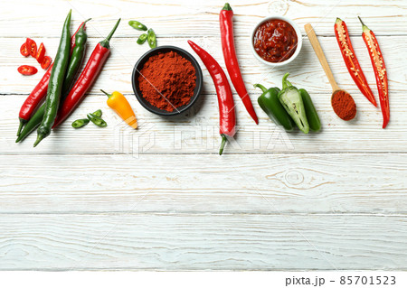 Hot peppers, sauce and powder on white wooden background 85701523