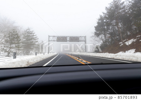 道路わきに雪の積もった、霧の濃い京都縦貫道を走る自動車の助手席からの風景 85701893