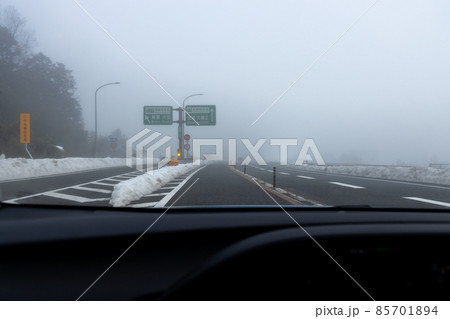 道路わきに雪の積もった、霧の濃い京都縦貫道を走る自動車の助手席からの風景 85701894