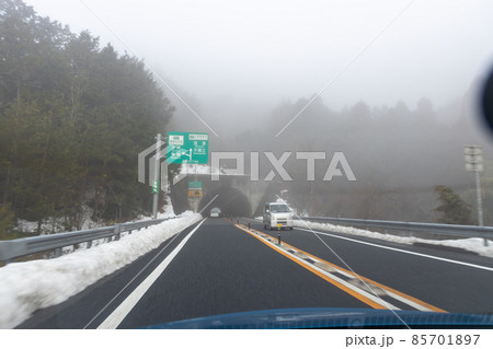 道路わきに雪の積もった、霧の濃い京都縦貫道を走る自動車の助手席からの風景 85701897