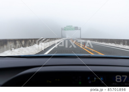 道路わきに雪の積もった、霧の濃い京都縦貫道を走る自動車の助手席からの風景 85701898