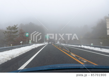 道路わきに雪の積もった、霧の濃い京都縦貫道を走る自動車の助手席からの風景 85701900
