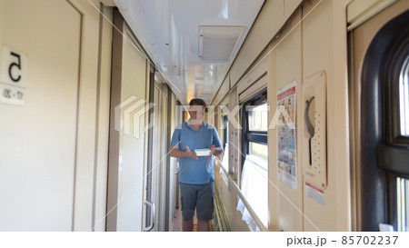 A man slowly walks with hot instant noodles along the corridor of a moving train 85702237