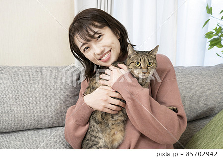 ソファーに座って猫を抱く女性 85702942