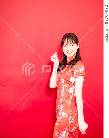 Beauty young woman wear cheongsam and hold mini heart in chinese new year on red background. 85704032