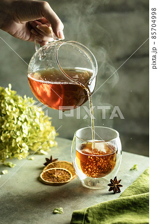Tea brewing process. A cup of freshly sourced tea with bubbles and steam on textured background Tea brewing process. A cup of freshly sourced tea with bubbles and steam on textured background 85704998