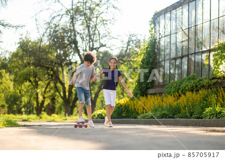 Cheerful girl teaching a boy to skateboard 85705917