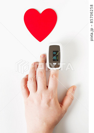 Covid Valentine day concept, hand with pulse oximeter on a finger and a heart symbol Covid Valentine day concept, hand with pulse oximeter on a finger and a heart symbol 85706258