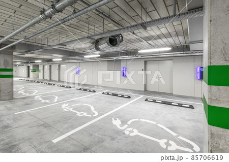 Empty public underground parking lot or garage interior with concrete stripe painted columns and signs. Electric car charging place. 85706619