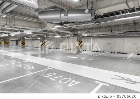 Empty public underground parking lot or garage interior with concrete stripe painted columns and signs. 85706620
