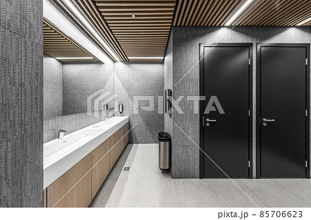 Interior of a modern public restroom with wood and grey clay elements and black doors 85706623