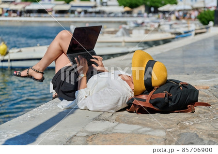 Woman in hat typing on laptop, water bay boat background Woman in hat typing on laptop, water bay boat background 85706900