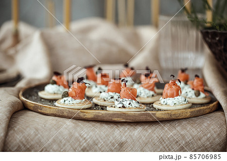 Handmade craft plate and salmon one bite snack on it, on linen tablecloth in earth tones boho style Handmade craft plate and salmon one bite snack on it, on linen tablecloth in earth tones boho style 85706985