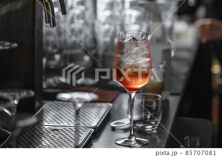 Bartender making aperol spritz summer cocktail in big wine glass Bartender making aperol spritz summer cocktail in big wine glass 85707081
