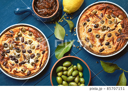 Homemade tart with olives on old blue wooden background decorated with fresh lemon, fresh olives, lemon leafs and fig jam from above Homemade tart with olives on old blue wooden background decorated with fresh lemon, fresh olives, lemon leafs and fig jam from above 85707151