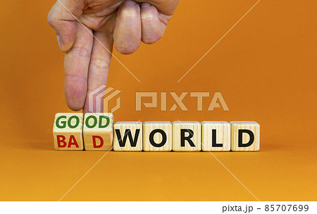 Good or bad world symbol. Businessman turns wooden cubes and changes words 'bad world' to 'good world'. Beautiful orange table, orange background, copy space. Business and good or bad world concept. 85707699
