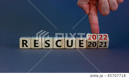 2022 rescue new year symbol. Businessman turns wooden cubes and changes words 'rescue 2021' to 'rescue 2022'. Beautiful grey background, copy space. Business, 2022 rescue new year concept. 2022 rescue new year symbol. Businessman turns wooden cubes and changes words 'rescue 2021' to 'rescue 2022'. Beautiful grey background, copy space. Business, 2022 rescue new year concept. 85707718