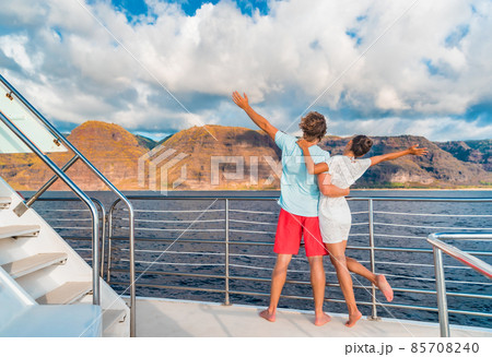 Couple on luxury yacht cruise ship tour at sunset feeling free happy with open arms in fun looking at mountain scenery. Romantic sunset boat ride watching view from deck on travel vacation Couple on luxury yacht cruise ship tour at sunset feeling free happy with open arms in fun looking at mountain scenery. Romantic sunset boat ride watching view from deck on travel vacation 85708240