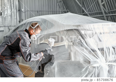Painting the rear part of the car. Car painter wearing costume and protective gear. Car service station. Restoring a car after an accident 85708676