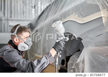Painting the rear part of the car. Car painter wearing costume and protective gear. Car service station. Restoring a car after an accident Painting the rear part of the car. Car painter wearing costume and protective gear. Car service station. Restoring a car after an accident 85708677