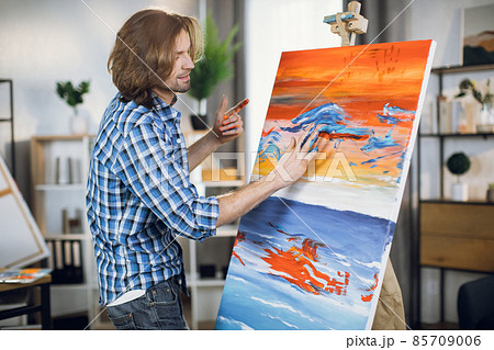 Inspired man drawing with hands on easel 85709006