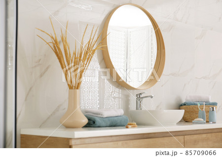 Round mirror over vessel sink in stylish bathroom 85709066