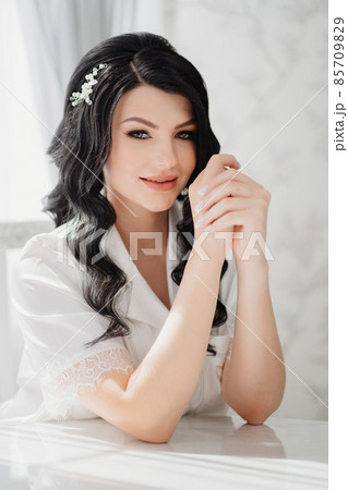 brunette bride in white silk pajamas with styling and makeup at the table brunette bride in white silk pajamas with styling and makeup at the table 85709829