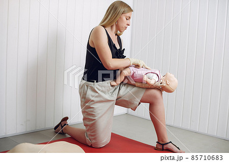 Woman learns to do artificial respiration on a mannequin. 85710683