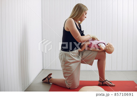 Woman learns to do artificial respiration on a mannequin. Woman learns to do artificial respiration on a mannequin. 85710691