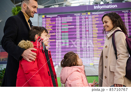 Happy multiracial family traveling together standing in front of the check-in board in the airport departure hall. Beautiful woman and man with their children checking the flight information schedule Happy multiracial family traveling together standing in front of the check-in board in the airport departure hall. Beautiful woman and man with their children checking the flight information schedule 85710767