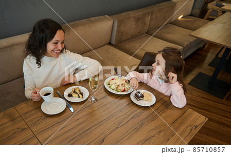 Mom and daughter having lunch together at a restaurant in the airport departure terminal while waiting to board the flight. Beautiful woman travels with her adorable little girl, having a snack 85710857
