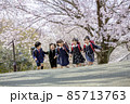桜の咲く公園を走る新一年生 85713763