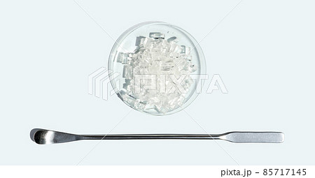 Closeup chemical ingredient on white laboratory table. Sodium Thiosulfate in Chemical Watch Glass placed next to the stainless spatula. Top View Closeup chemical ingredient on white laboratory table. Sodium Thiosulfate in Chemical Watch Glass placed next to the stainless spatula. Top View 85717145