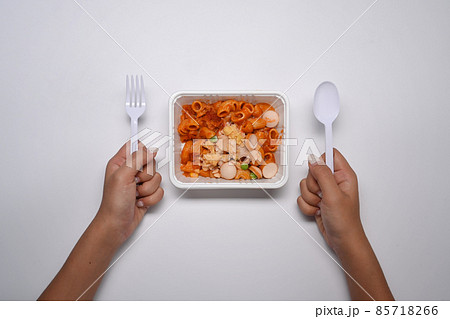 Above view woman holding spoon and fork ready to microwave and eat macaroni pasta with tomato sauce. Above view woman holding spoon and fork ready to microwave and eat macaroni pasta with tomato sauce. 85718266