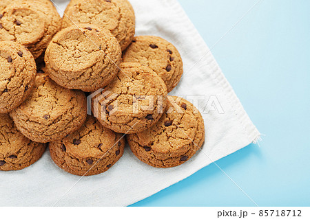 A bunch of oatmeal cookies with chocolate on a napkin on a blue background 85718712