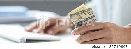 Dollars in woman hand and computer keyboard on table Dollars in woman hand and computer keyboard on table 85719893