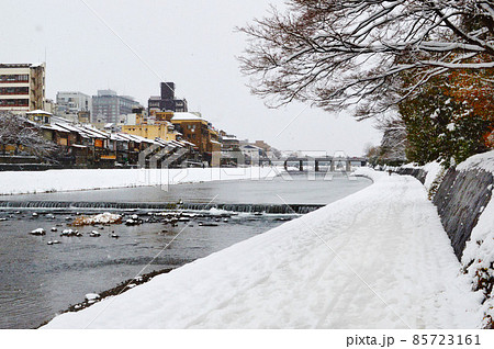 冬の早朝に雪舞う京都市鴨川の遊歩道を三条大橋に向かう 85723161