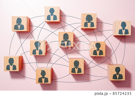 調和のとれたチームや良い連携のイメージ。人のアイコンが描かれた多数の積み木。木のテーブルの俯瞰。 85724235