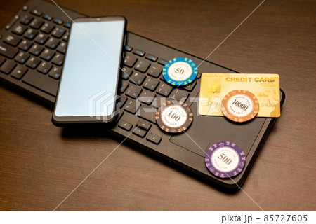 Online casino theme. Smartphone, credit card and poker chips lie on the computer keyboard 85727605