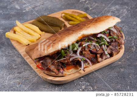 Turkish Doner with veal in a pit with French fries, pickles and red onions 85728231