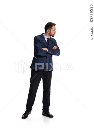 Full-length portrait of businessman with curious and concentrated facial expression controlling projects isolated over white background Full-length portrait of businessman with curious and concentrated facial expression controlling projects isolated over white background 85729559