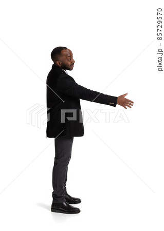 Full-length side view portait of businessman lending hand for shaking isolated over white background Full-length side view portait of businessman lending hand for shaking isolated over white background 85729570