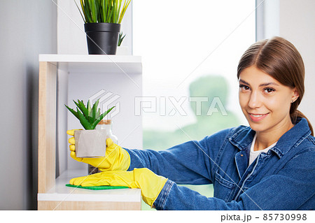 Pretty woman in uniform with supplies cleaning in office 85730998