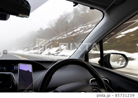 道路わきに雪の積もった、霧の濃い見通しの悪い京都縦貫道を走る自動車の助手席からの風景 85731239