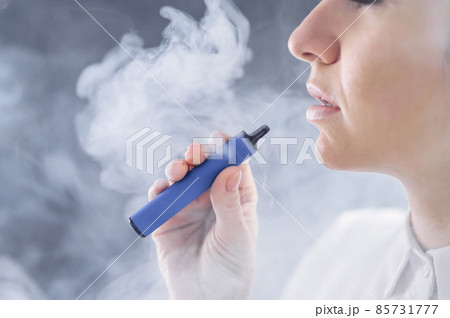 Caucasian woman smokes a disposable vape in the studio. Caucasian woman smokes a disposable vape in the studio. 85731777