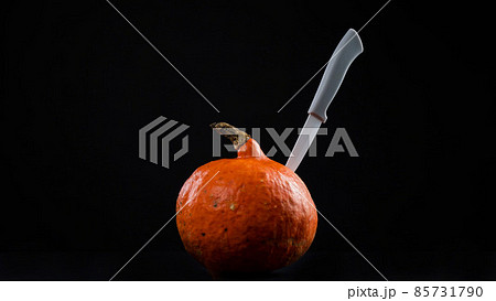 Knife in a pumpkin on a black background. Halloween symbol. Isolate. Knife in a pumpkin on a black background. Halloween symbol. Isolate. 85731790